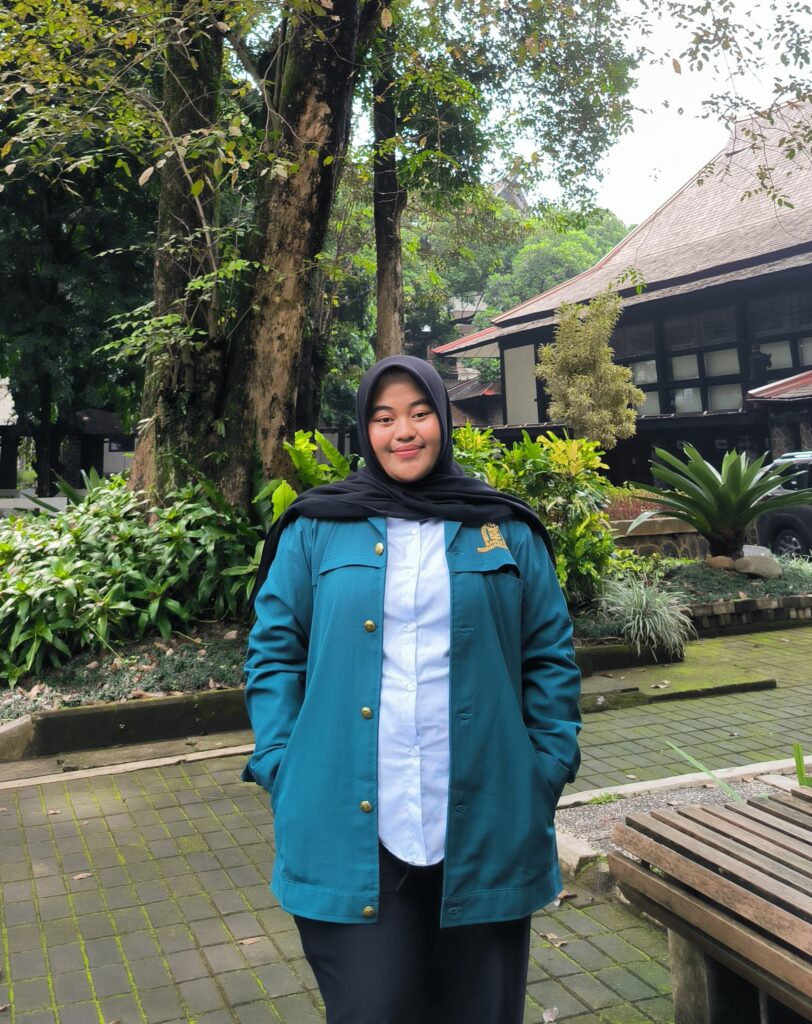 Sarah berdiri menggunakan jaket almamater kampus Institut Teknologi Bandung
